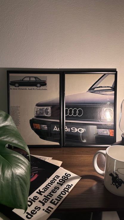 Gerahmte Oldtimer-Werbung des Audi 90, stilvoll auf einem Tisch präsentiert, umgeben von Vintage-Magazinen und einer Tasse. Perfektes Ambiente, das die klassische Eleganz des Posters zur Geltung bringt.