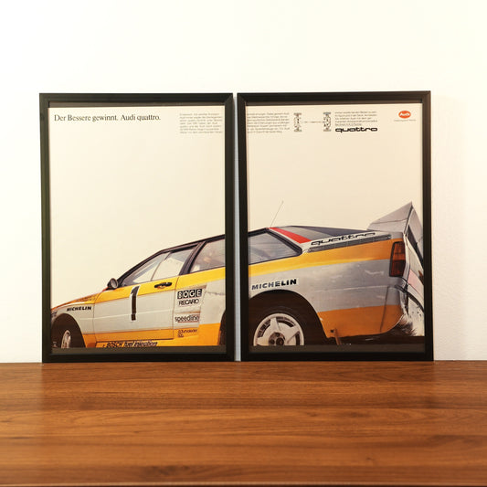 Original vintage Audi quattro advertisement framed in black aluminum. Two-piece wall art set showing the side profile of a white and yellow Audi quattro with rally decals and the German slogan 'Der Bessere gewinnt'.