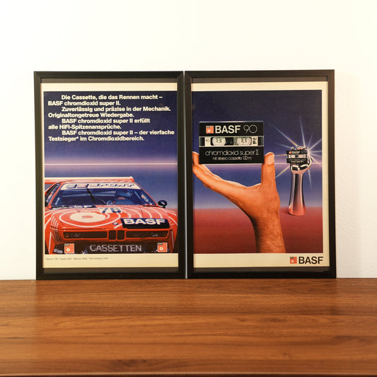 Original vintage BASF advertisement framed in black aluminum. Two-piece wall art set featuring a red BMW M1 Procar race car on the left and a hand holding a BASF 90 chrome cassette on the right.