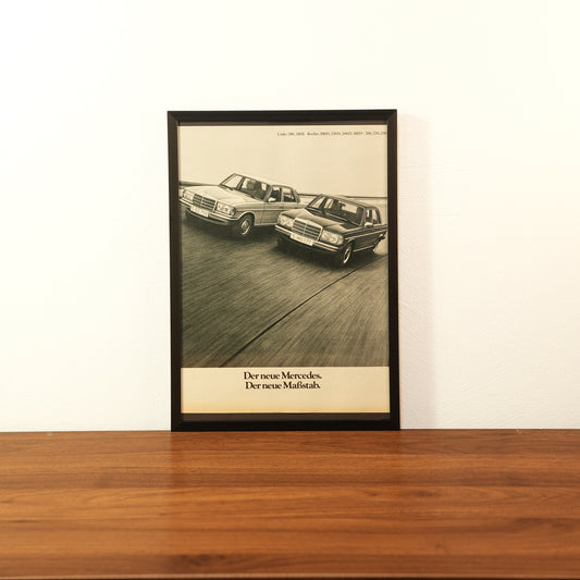 Original vintage Mercedes-Benz W123 advertisement framed in black aluminum. Single wall art piece showing two Mercedes sedans driving on a track with the German slogan 'Der neue Mercedes. Der neue Maßstab.