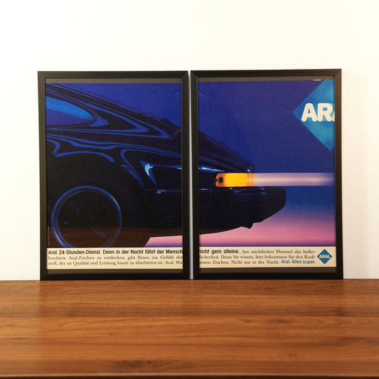 Original vintage Porsche 911 advertisement framed in black aluminum. Two-piece diptych wall art set showing a dark blue Porsche 911 rear at night with the Aral logo and German slogan 'Aral 24-Stunden-Dienst'
