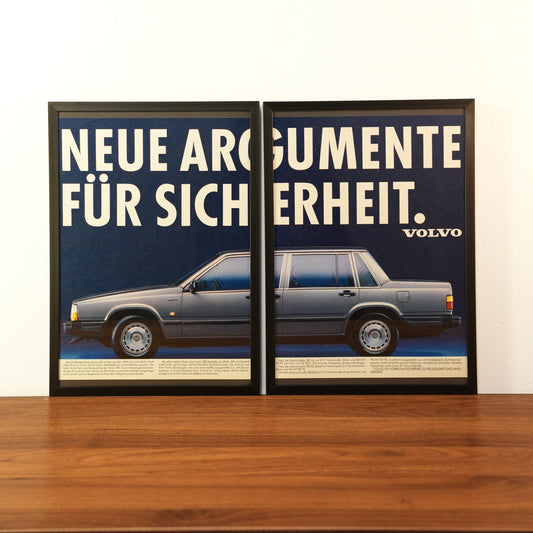 Original vintage Volvo advertisement framed in black aluminum. Two-piece wall art set showing the side profile of a grey Volvo sedan with the large German headline 'NEUE ARGUMENTE FÜR SICHERHEIT'.